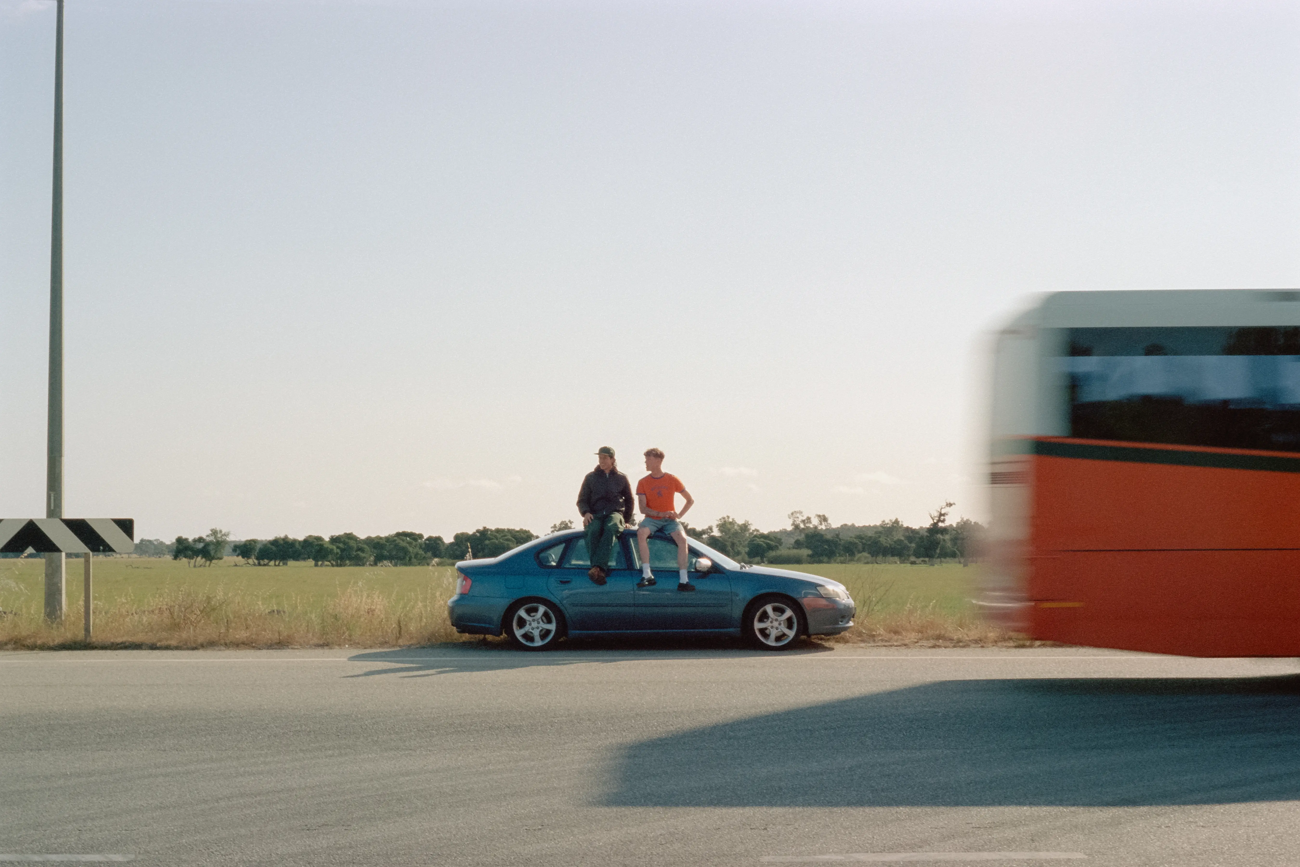 carlo and clark sit on the roof of their car